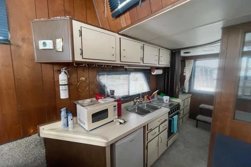 Slide: The Image of Interior of a 1991 Gibson 37 Standard Houseboat kitchen with wood paneling and appliances. - 7