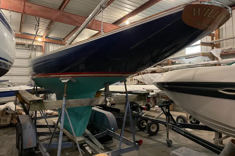 Slide: The Image of 1965 Chris Craft Shields sailboat in storage, blue hull, green keel, on trailer. - 4