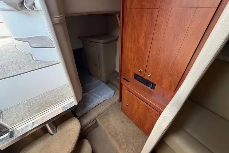Slide: The Image of Interior of 2006 Rinker 300 Express Cruiser with wooden cabinetry and cozy sleeping area. - 13