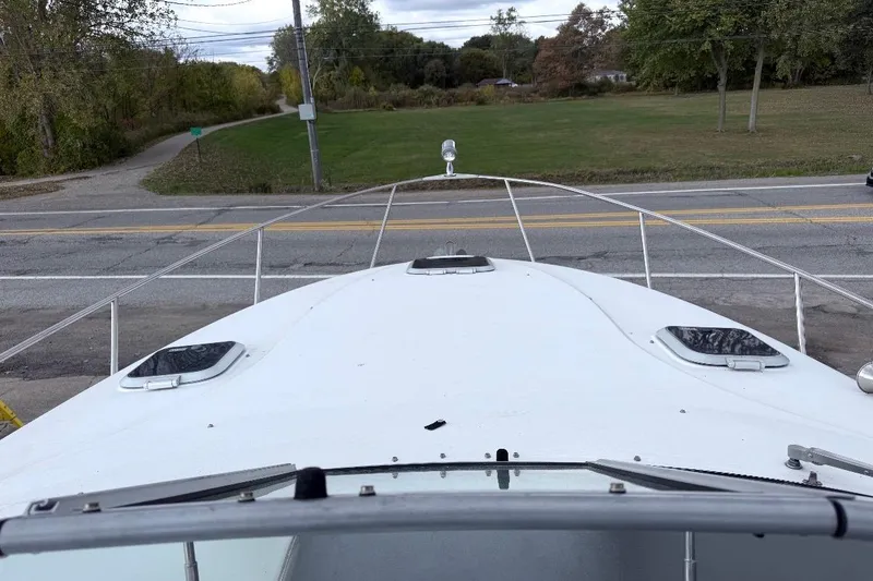 Slide: The Image of 2006 Rinker 300 Express Cruiser boat docked near a road, surrounded by greenery. - 15