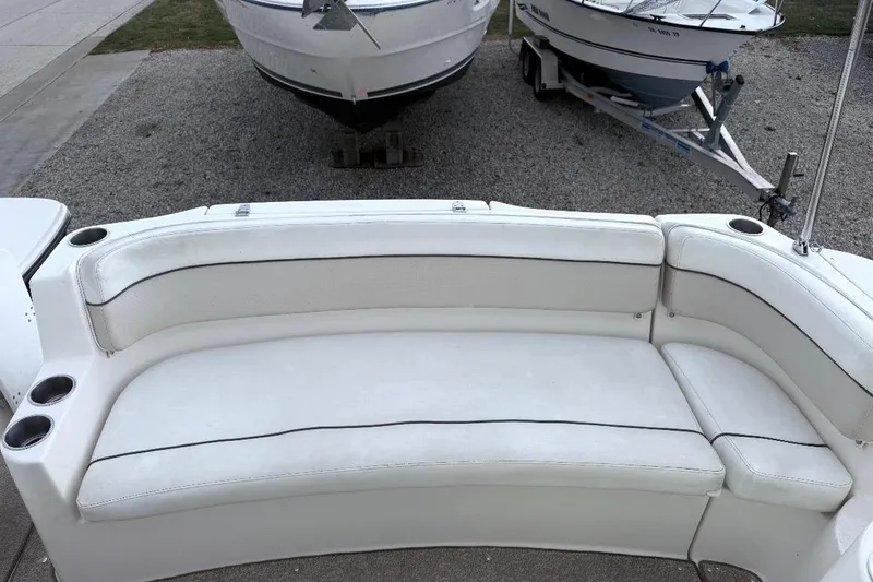 Slide: The Image of 2006 Rinker 300 Express Cruiser interior seating with cup holders, parked on gravel. - 19