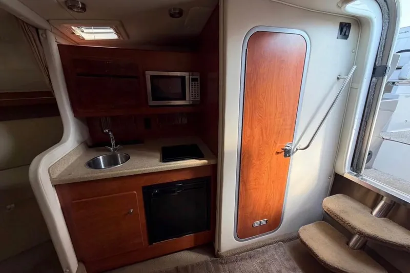 Slide: The Image of 2006 Rinker 300 Express Cruiser interior with kitchenette, microwave, and wooden cabinetry. - 9