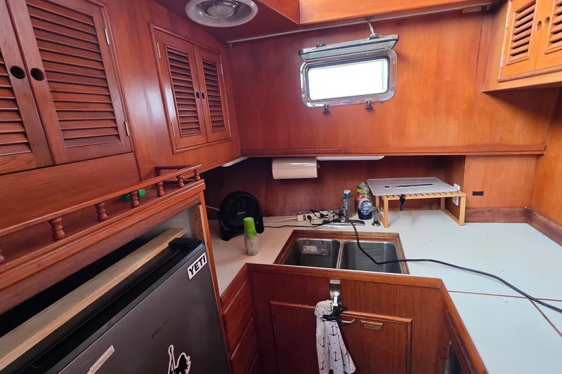 Slide: The Image of Interior of a 1991 Marine Trader Trawler kitchen with wooden cabinets and a small sink. - 11