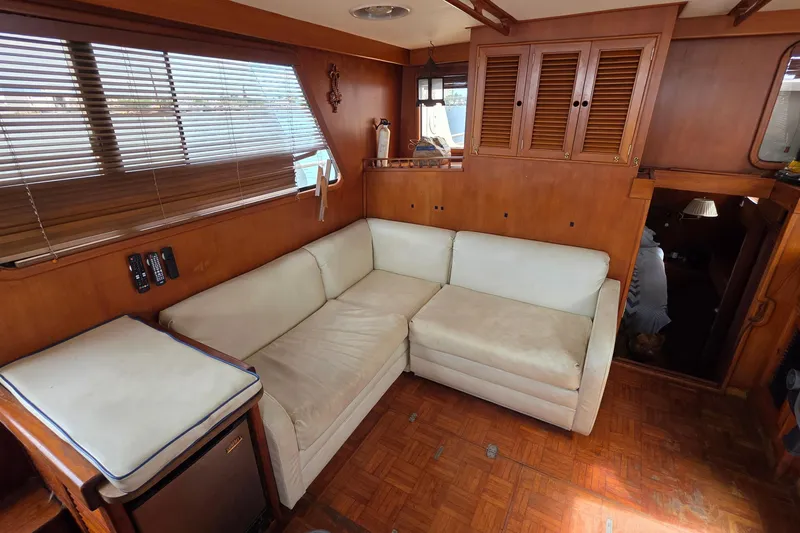 Slide: The Image of Interior of a 1991 Marine Trader Trawler with a cozy white sofa and wooden cabinetry. - 13