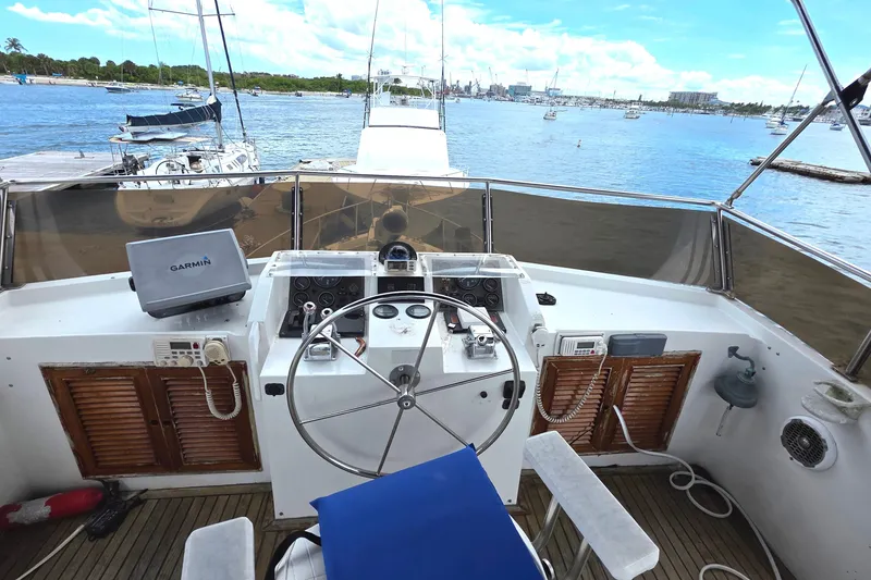 Slide: The Image of 1991 Marine Trader Trawler helm with Garmin navigation, overlooking a scenic marina. - 32