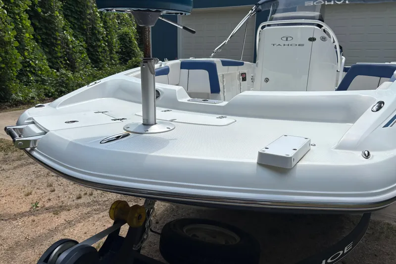 Slide: The Image of 2020 Tahoe 2150 CC boat with white deck and blue seating, parked outdoors. - 31