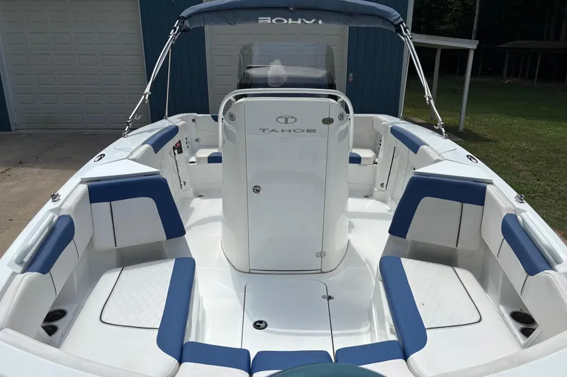 Slide: The Image of 2020 Tahoe 2150 CC boat interior with blue and white seating, docked near a garage. - 32