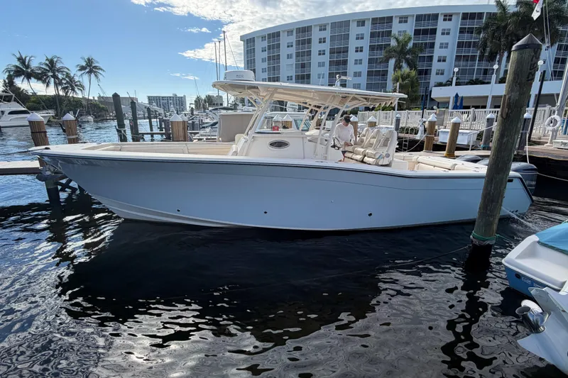 The Image of 2016 Grady-White Canyon 336 boat docked at marina with palm trees and buildings. - 1