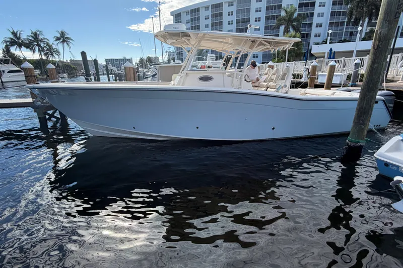 Slide: The Image of 2016 Grady-White Canyon 336 boat docked at marina with palm trees and buildings. - 2