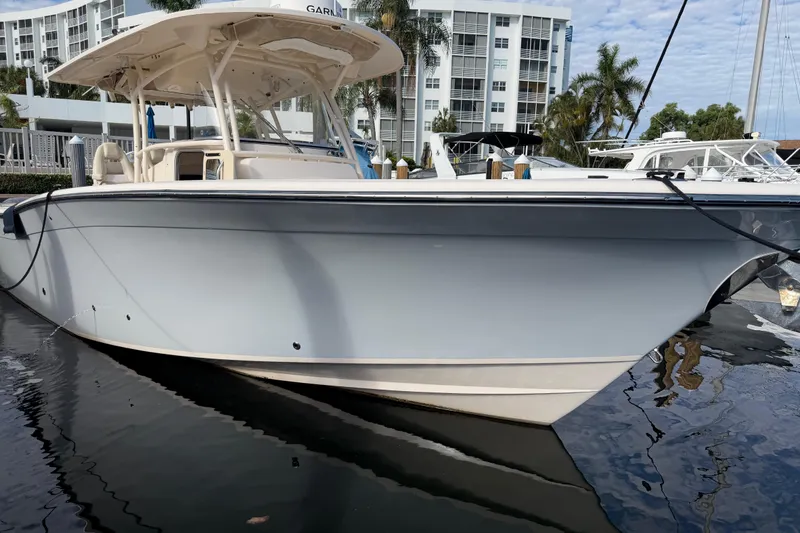 Slide: The Image of 2016 Grady-White Canyon 336 boat docked in marina, with modern buildings in background. - 8