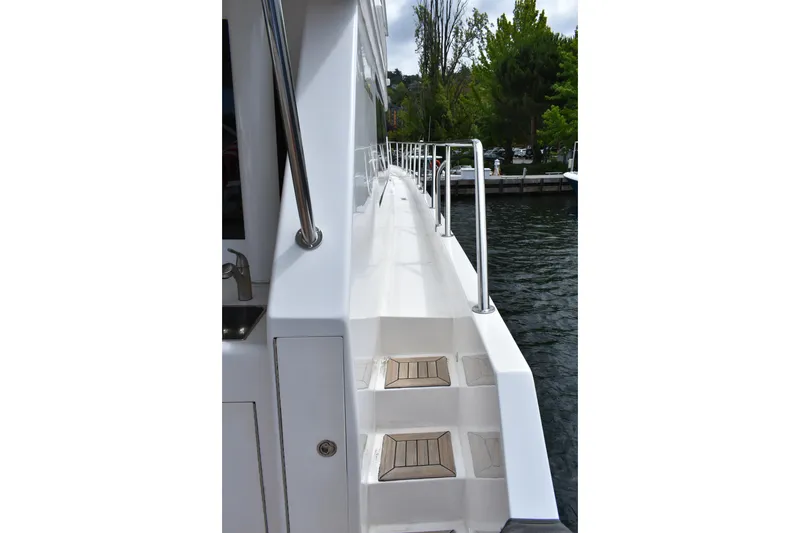 Slide: The Image of Side deck view of 2004 Ocean Alexander 64 Pilothouse yacht, featuring sleek white design and railing. - 14