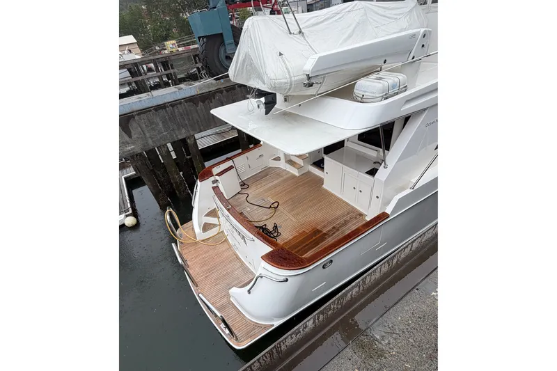 Slide: The Image of 2004 Ocean Alexander 64 Pilothouse yacht docked, featuring spacious deck and covered upper area. - 95