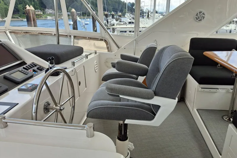 Slide: The Image of Pilothouse interior of 2004 Ocean Alexander 64, featuring helm, seating, and scenic marina view. - 21