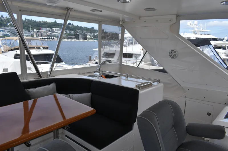 Slide: The Image of Interior of a 2004 Ocean Alexander 64 Pilothouse with table, seating, and a view of the marina. - 26