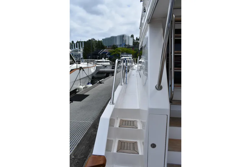 Slide: The Image of 2004 Ocean Alexander 64 Pilothouse yacht docked, showcasing sleek side deck and stainless steel railings. - 11