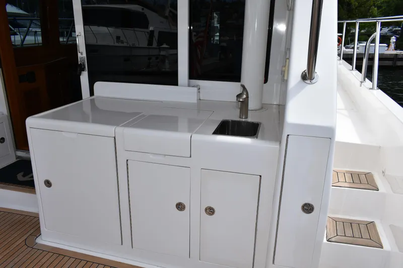 Slide: The Image of Outdoor kitchenette on 2004 Ocean Alexander 64 Pilothouse yacht with sink and storage cabinets. - 17