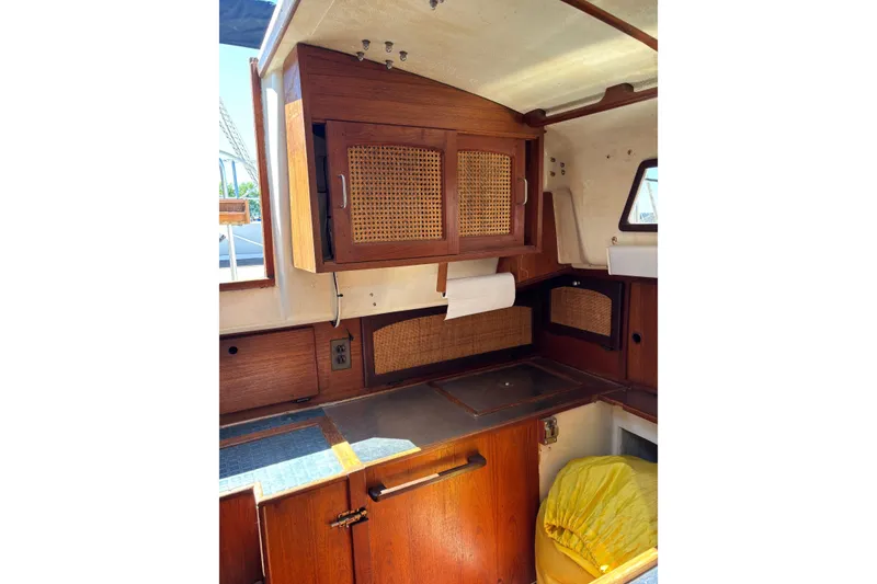 Slide: The Image of Interior of a 1979 Aloha 34 sailboat featuring wooden cabinetry and a compact kitchen area. - 15