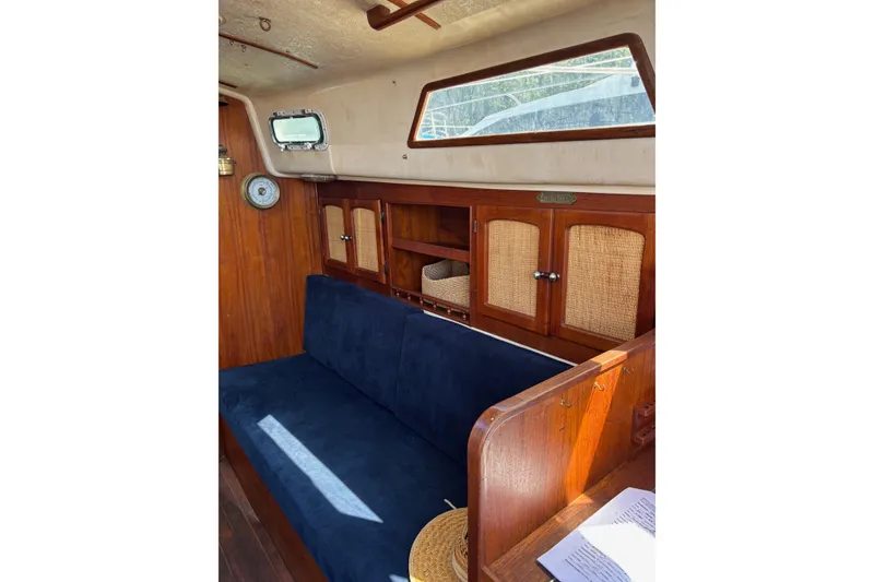 Slide: The Image of Interior of a 1979 Aloha 34 sailboat with wooden cabinetry and blue seating. - 17