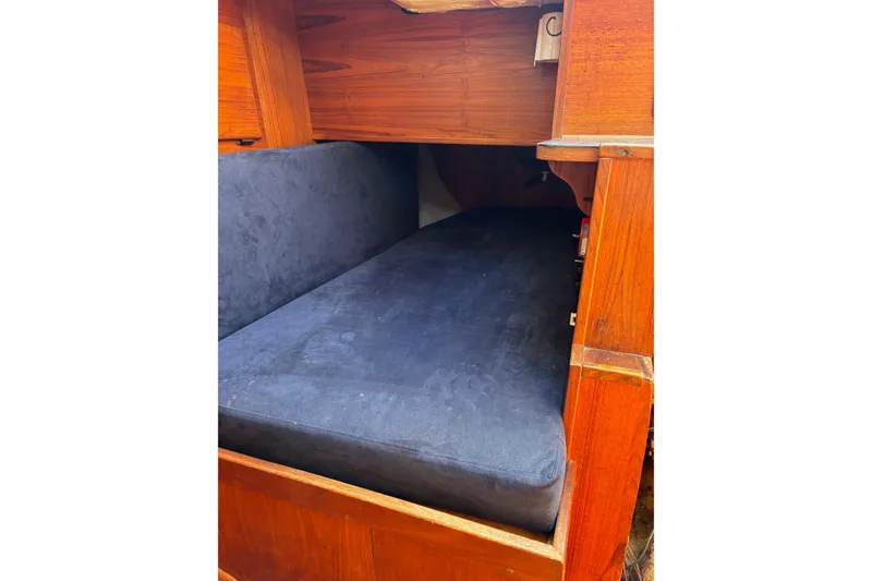 Slide: The Image of 1979 Aloha 34 sailboat interior with wooden bunk and dark cushion. - 22