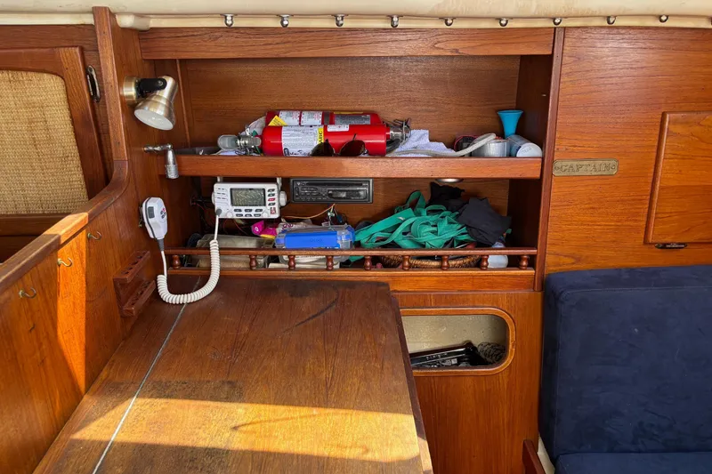 Slide: The Image of 1979 Aloha 34 yacht interior with wooden shelves, radio, and safety equipment. - 23