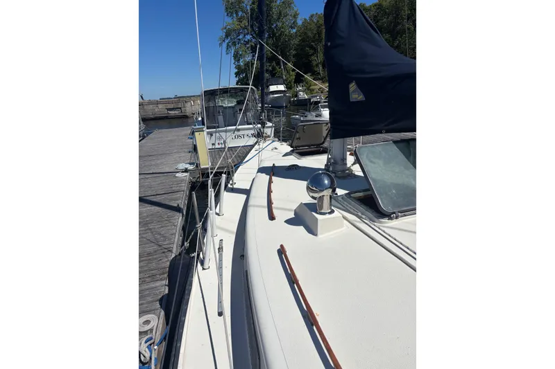 Slide: The Image of 1979 Aloha 34 sailboat docked, showcasing deck and rigging under clear blue sky. - 30