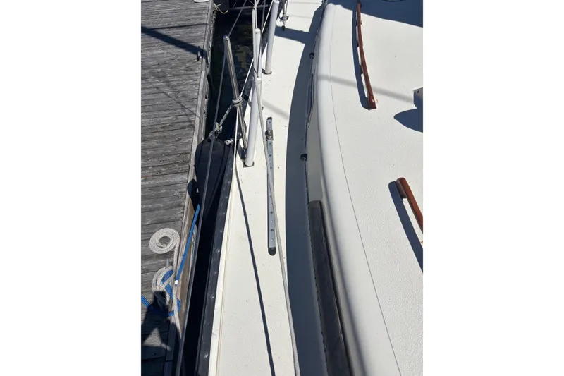 Slide: The Image of 1979 Aloha 34 sailboat deck view, docked with visible rigging and wooden handrails. - 32