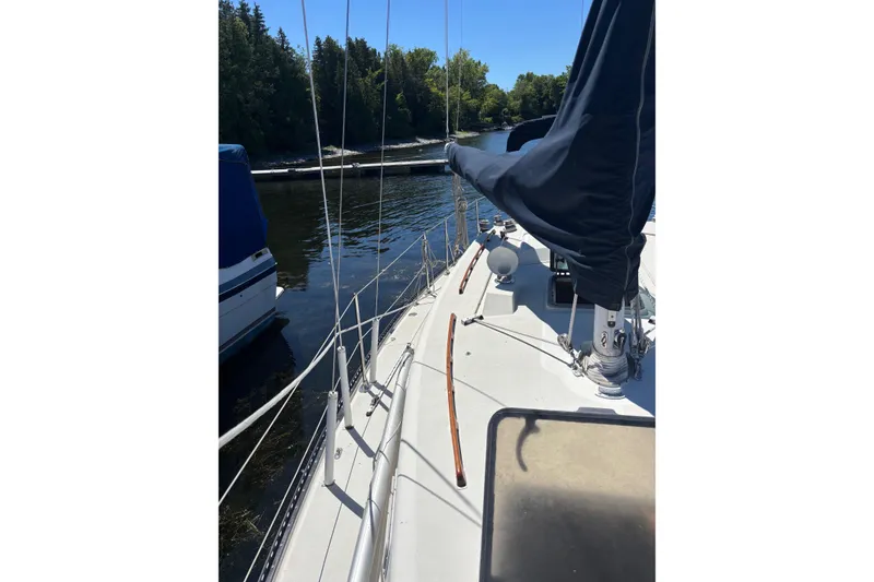 Slide: The Image of 1979 Aloha 34 sailboat docked, featuring deck view with rigging and forest backdrop. - 38
