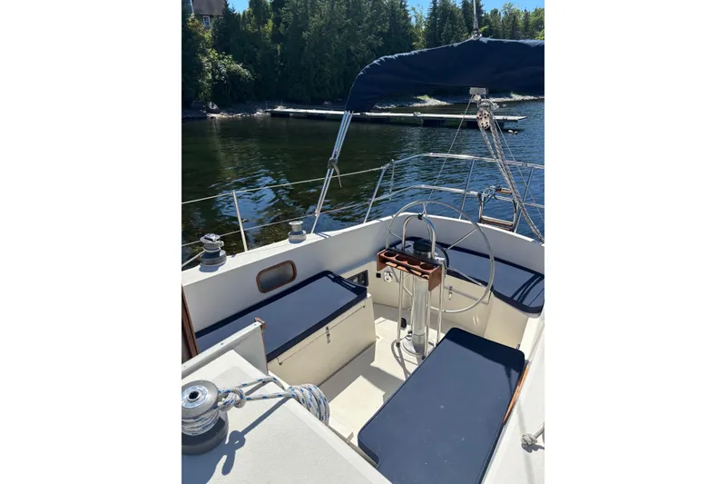 Slide: The Image of Cockpit of a 1979 Aloha 34 sailboat with blue seating, docked by a forested shoreline. - 39