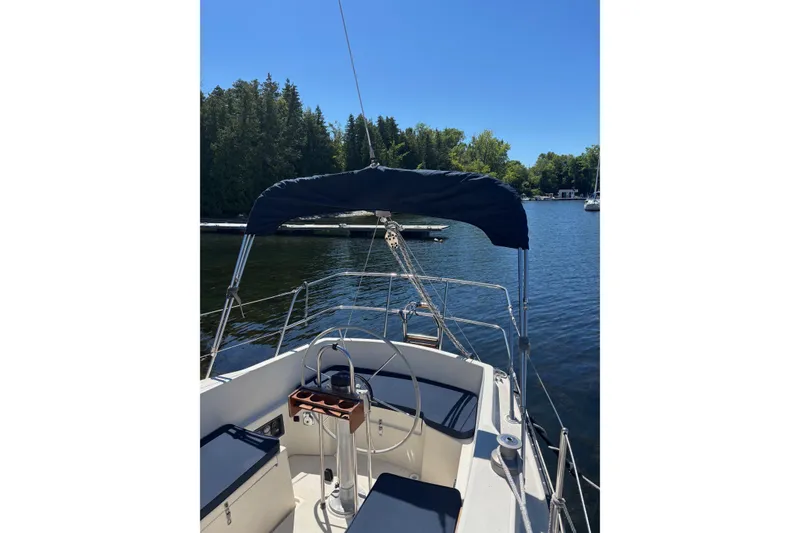 Slide: The Image of 1979 Aloha 34 sailboat on a serene lake with lush green trees. - 40