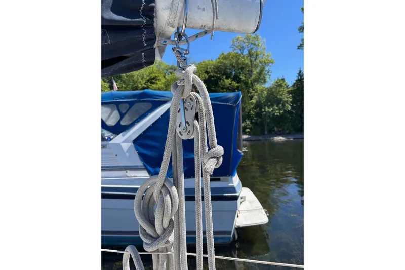 Slide: The Image of Rope and pulley system on a 1979 Aloha 34 sailboat, docked near lush greenery. - 44
