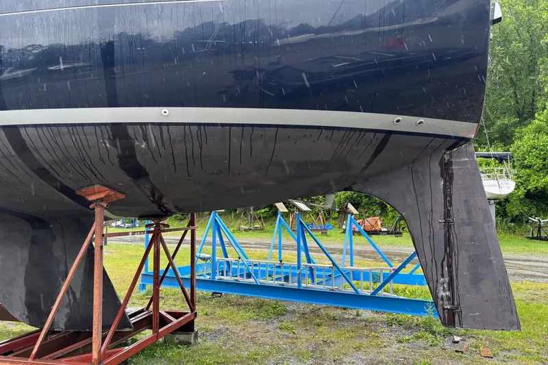Slide: The Image of 1979 Aloha 34 sailboat hull on stands, displayed outdoors with greenery in the background. - 6