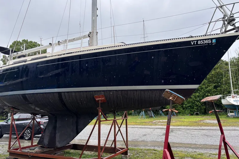 Slide: The Image of 1979 Aloha 34 sailboat on stands, dark hull, parked outdoors. - 7