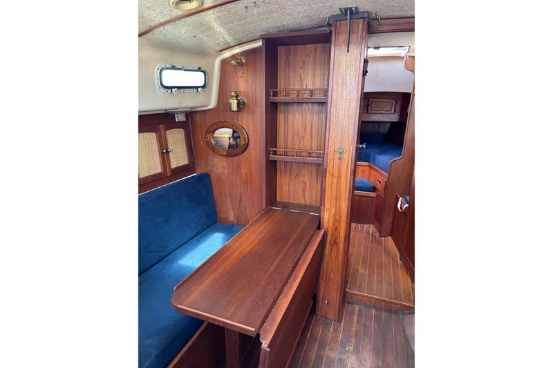 Slide: The Image of Interior of a 1979 Aloha 34 sailboat with wooden furnishings and blue seating. - 8
