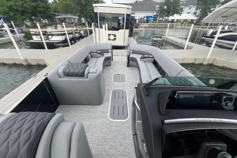 Slide: The Image of Luxurious 2026 Bennington RX 25 RXSBA pontoon boat with spacious seating at a marina. - 11