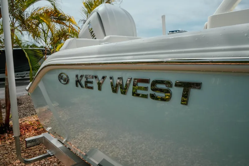Slide: The Image of 2026 Key West 239 FSR boat with logo, parked outdoors near palm trees. - 11