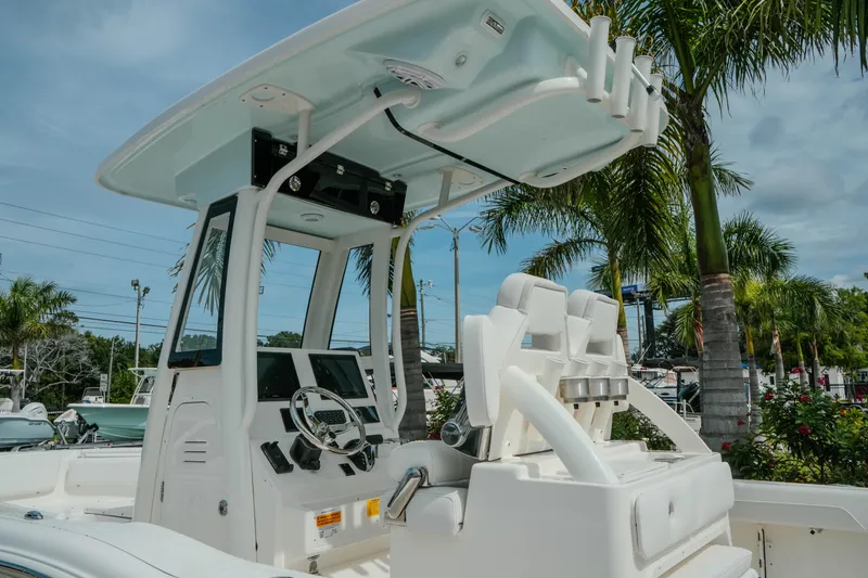 Slide: The Image of 2026 Key West 239 FSR boat cockpit with helm, seats, and palm trees in background. - 16