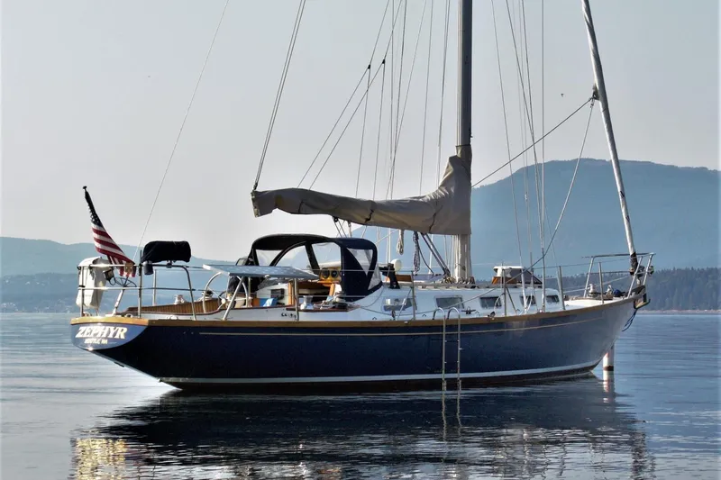 The Image of Sailboat Ohlson 38, 1984 model, anchored on calm water with mountainous backdrop. - 0