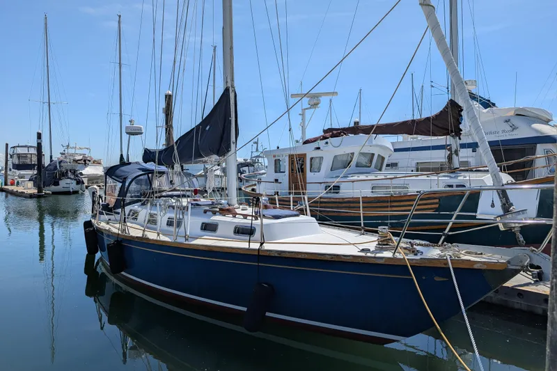 Slide: The Image of 1984 Ohlson 38 sailboat docked in a marina, surrounded by other boats. - 1