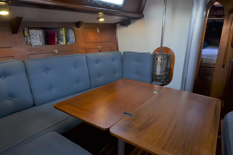 Slide: The Image of Cozy interior of 1984 Ohlson 38 sailboat with wooden table and cushioned seating. - 11