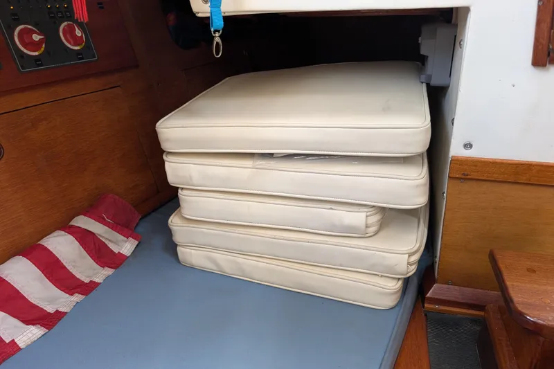 Slide: The Image of Stacked white cushions inside a 1984 Ohlson 38 sailboat cabin. - 16