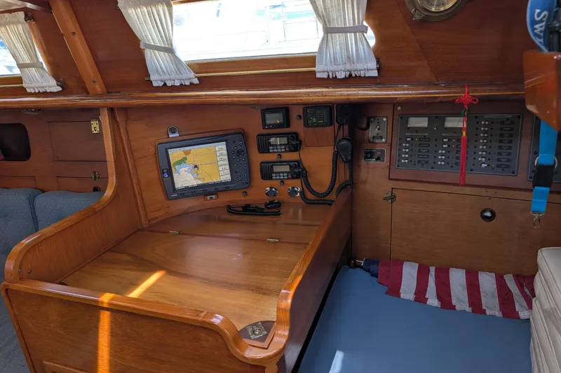 Slide: The Image of Navigation station inside a 1984 Ohlson 38 sailboat with electronic equipment and wooden interior. - 22