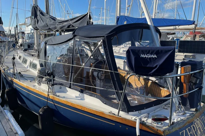 Slide: The Image of 1984 Ohlson 38 sailboat docked, featuring a blue hull and covered cockpit. - 3
