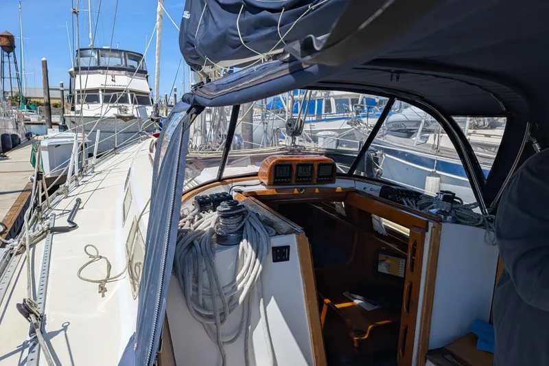 Slide: The Image of 1984 Ohlson 38 sailboat cockpit with ropes and navigation instruments at a marina. - 35