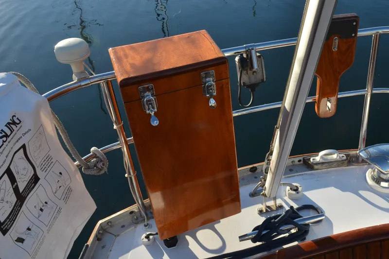 Slide: The Image of Wooden helm station on 1984 Ohlson 38 sailboat, featuring polished metal fittings and safety equipment. - 4