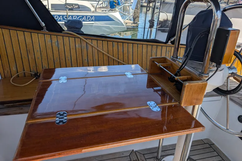 Slide: The Image of Polished wooden table on 1984 Ohlson 38 sailboat deck, with nautical equipment. - 48