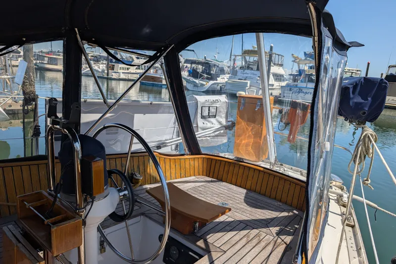 Slide: The Image of Cockpit of 1984 Ohlson 38 sailboat docked at marina, featuring steering wheel and clear canopy. - 49