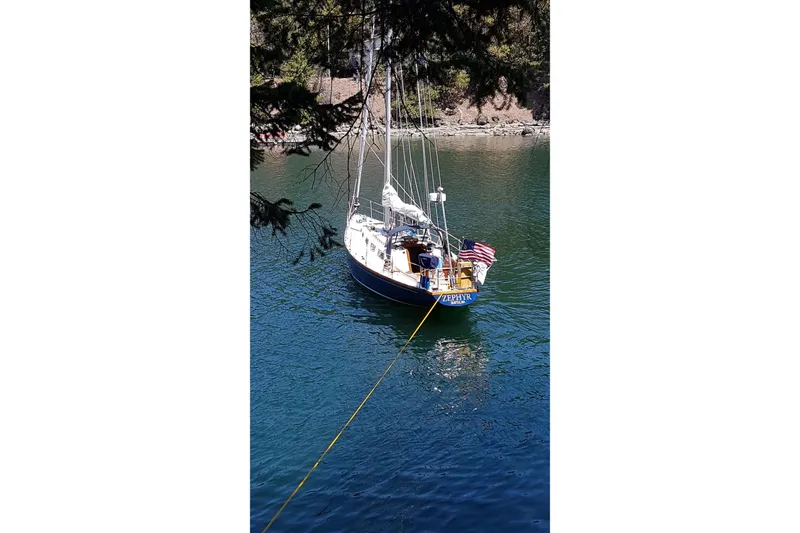 Slide: The Image of Sailboat Ohlson 38 (1984) anchored in serene waters, surrounded by trees. - 54