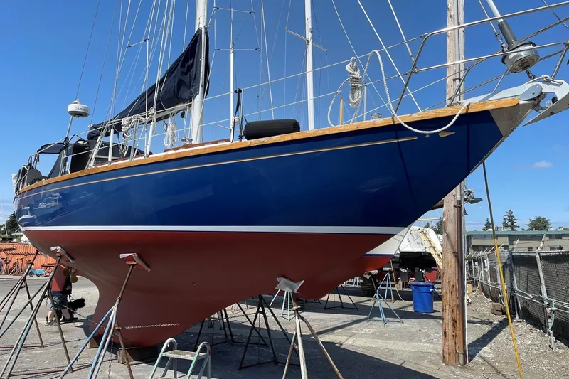 Slide: The Image of 1984 Ohlson 38 sailboat on dry dock, blue hull, red bottom, clear sky. - 58