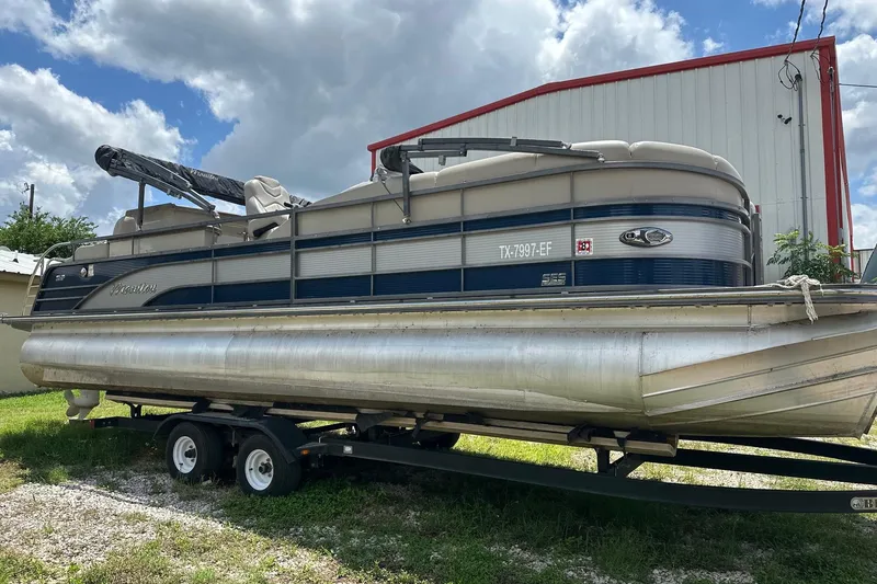 Slide: The Image of 2017 Manitou 25 SES pontoon boat on trailer, parked outdoors under cloudy sky. - 3