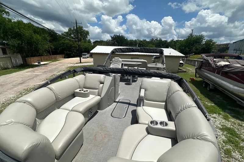 Slide: The Image of 2017 Manitou 25 SES pontoon boat with spacious seating and cup holders under a cloudy sky. - 4